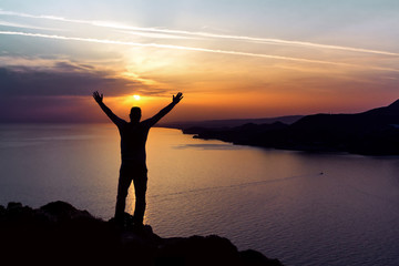 Fototapeta premium Silhouette of a man on the background of the sunset sun setting in the sea
