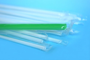 White and green plastic drinking straw on blue background