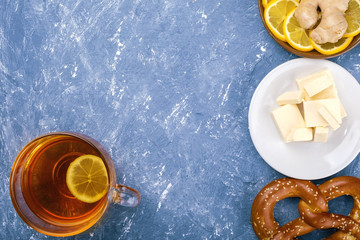 Fresh traditional pretzel On blue textured background. Lemon, tea, ginger. Delicious breakfast. - Powered by Adobe