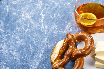 Fresh traditional pretzel On blue textured background. Lemon, tea, ginger. Delicious breakfast. - Powered by Adobe