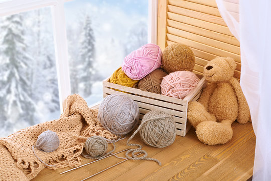 Woolen yarn and fabric on the window sill. Beautiful view outside the window - winter scenery and snow.