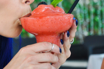 Disfrutando de un coktel una chica con uñas azules