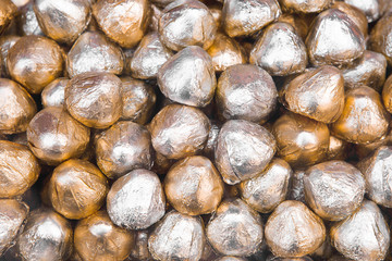 Chocolate Candies Or Sweets Wrapped In Gold And Silver Foil, Close Up. Beautiful Shiny Background. Wrapped Chocolate In Shiny Foil.