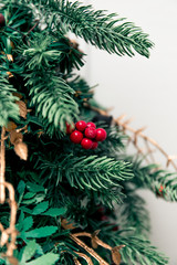 A Christmas tree decorated with red berries and golden beads, ornaments. Artificial branches and pine cones. Merry Christmas and Happy New Year. Interior decor.