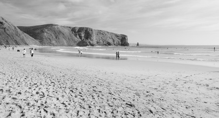 Beach in the Algarve region of Portugal. People swimming and surfing.  Black white photo.