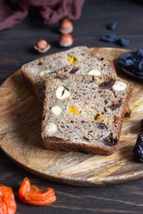 Bread with dried fruits and nuts on old wooden table. Homemade festive whole grain bread with dried fruits and nuts. Rustic style.
