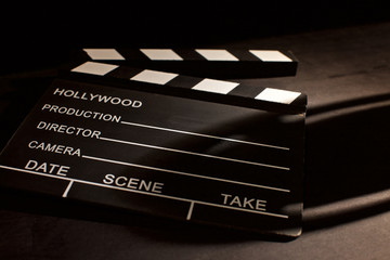 movie clapper with shadow on wooden black background