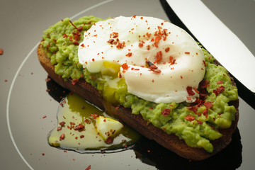 Avocado toast with minced pulp and poached egg and table knife