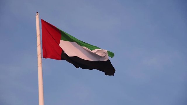 United Arab Emirates flag winding in the wind against blue sky