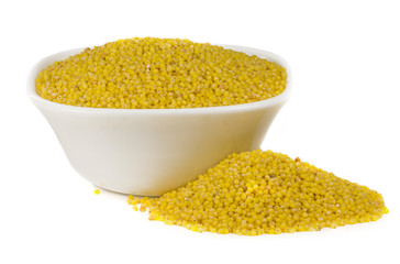 millet in white ceramic bowl isolated on white. Spilled millet. Yellow millet groats in ceramic bowl, isolated on white background