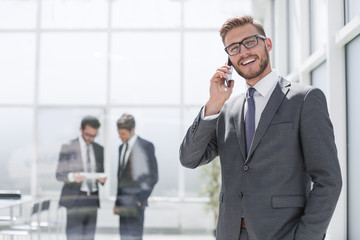 businessman with mobile phone standing next to the Bank office