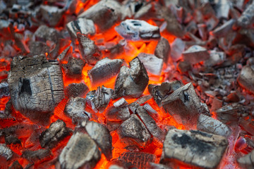 BBQ Grill Pit With Glowing And Flaming Or Burning Hot Coal Briquettes, Charcoal Background Or Texture, Close-Up, Front View.