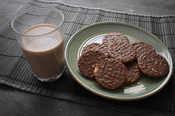 Plato con galletas de chocolate, vaso de leche con chocolate