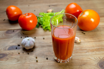 A glass of delicious tomato juice, fresh tomatoes and garlic