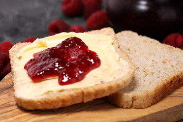 Toast bread with homemade raspberry jam or marmalade on rustic table served with butter for breakfast or brunch
