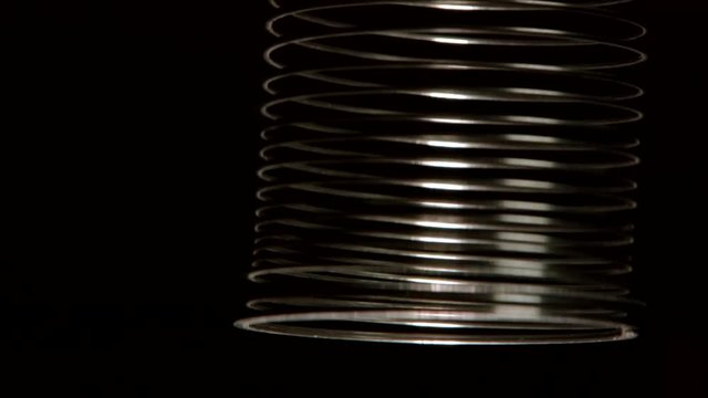 Metal spring going up and down. Isolated on black background.