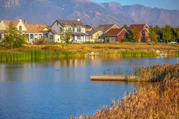 Fototapeta premium Wooden deck on lake with homes and mountain view