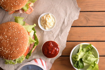 Two burgers with soda and souces on wood table background