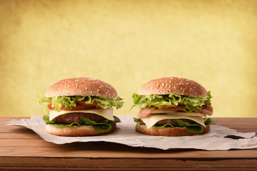 Two classic beef burger on wooden table and golden background