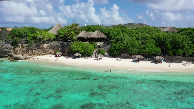 Aerial Rotating View of a Small Group of Tourists Enjoying a Perfect Day on a Tropical Beach in Cura&radic;&szlig;ao of the Caribbean Islands, Crystal Clear Blue Water