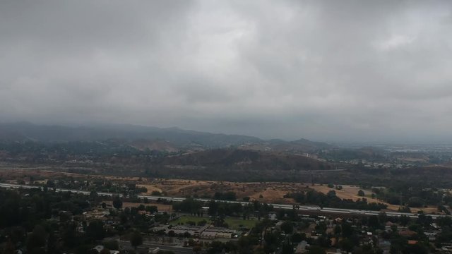 Aerial drone footage of the 210 freeway at Wheatland in Sylmar, California and the surrounding area on an overcast and cloudy day.