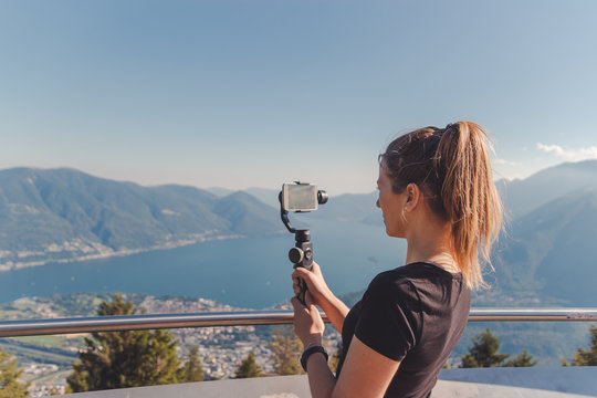 girl filming with gimbal in the mountains over lake maggiore