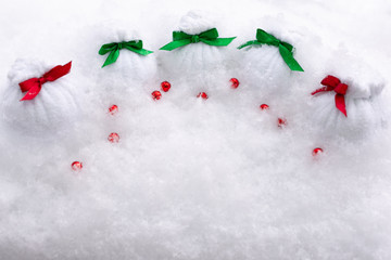 Santa Claus gifts are in bags with colorful bows and beads in a snowdrift.