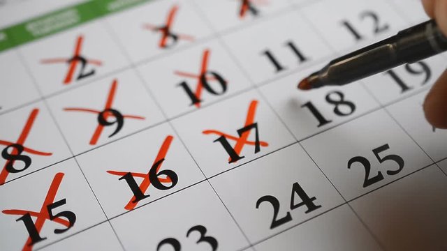 Signing a day on a calendar by red pen background