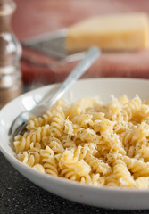 Close-up of a bowl of fusilli pasta served with butter and grated cheese