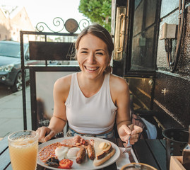 smiling young woman eating an english breakfast