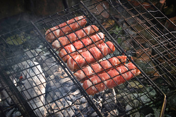 Grilling sausages wrapped becon on  grill