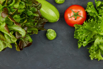 Group of fresh vegetables and lettuce on black background. there is room for text in the center. copyspace. vertical view. health food.