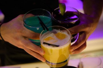 Men's arms holds three glasses with cocktails 