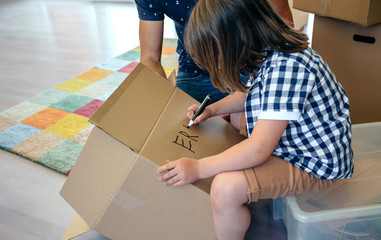 Little boy writing his name in a moving box with his father