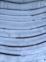 gefrohrene wasser lacke/pfütze im winter/muster in der winterlichen natur, gekrümmte linien, streifen aus eis