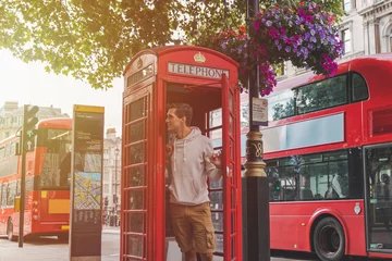 Tafelkleed young male in London looking out from a phone booth with red busses in the back © NDStock