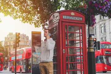 Rucksack kleiner Junge mit dem Smartphone vor einer Telefonzelle und einem roten Bus in London © NDStock