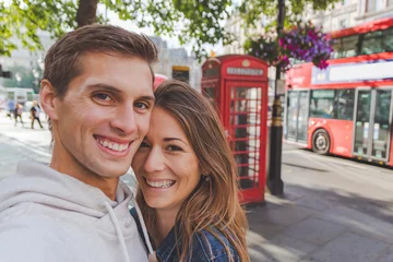 Photo sur Plexiglas Bus rouge de Londres Heureux jeune couple prenant un selfie devant une cabine téléphonique et un bus rouge à Londres
