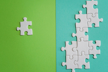 Fragment of a folded white jigsaw puzzle and a pile of uncombed puzzle elements against the...