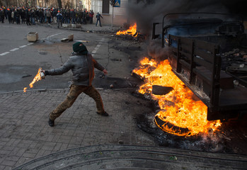 Street Protestant with a Molotov cocktail against a fire