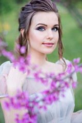 Naklejka premium Portrait of a beautiful girl in flowers. Professional makeup. Fashion model in work. Wedding make-up. Portrait of a stylish bride.