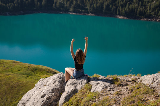 positive young woman enjoying freedom on the top of the mountain with the lake ritom as background