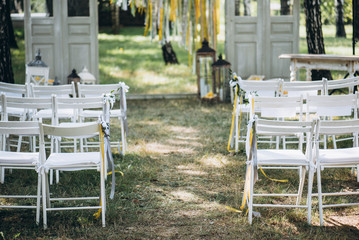 Fototapeta na wymiar Wedding ceremony. Festive arch. Beautiful wedding decor with many flowers, lemons, balloons, candles and chairs for guests. Celebration, outdoors