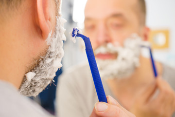 Guy shaving his beard in bathroom