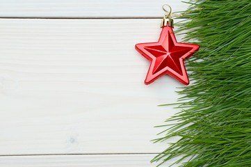 Fototapeta na wymiar Christmas and New Year trees branch and red star on a white wooden background.