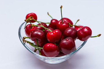 The glass bowl filled  with ripe cherries