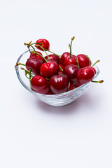 The glass bowl filled  with ripe cherries