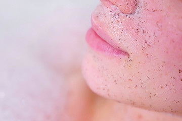 Scrub on woman's face. Lips close-up. Woman ia taking a bath.