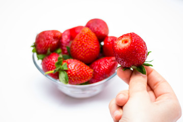 The girl taking strawberry from the bowl and eating it