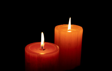 Obraz na płótnie Canvas Red an orange candle before the dark with black background
